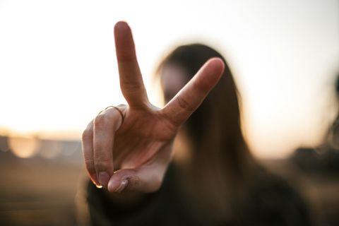 Person holding up a two-finger peace sign outdoors
